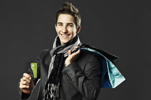 Young man holding debit card and shopping bags